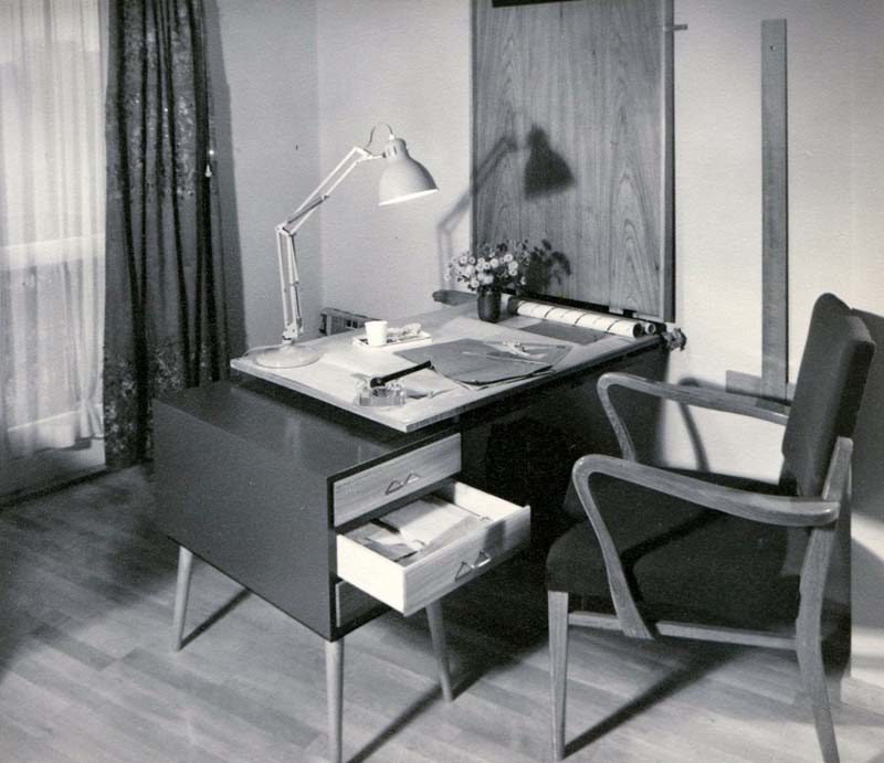 black and white photograph of desk, chair, and table lamp