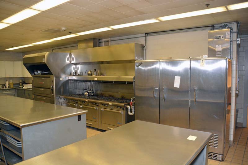 industrial kitchen with stainless steel cabinets, countertops, ovens, and stovetops