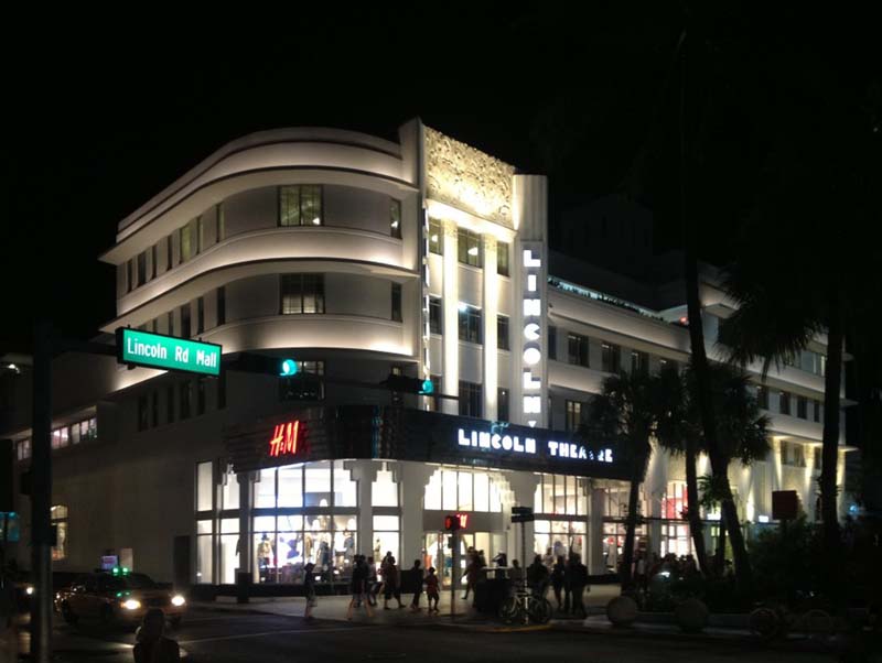 theater lit up at night at corner of intersection