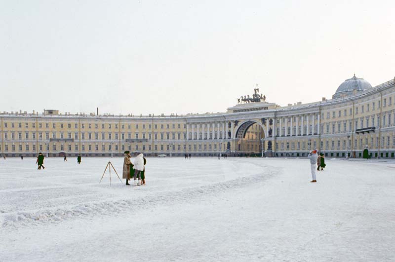 snow-covered plaza surrounded by curvlinear building with arched entrance